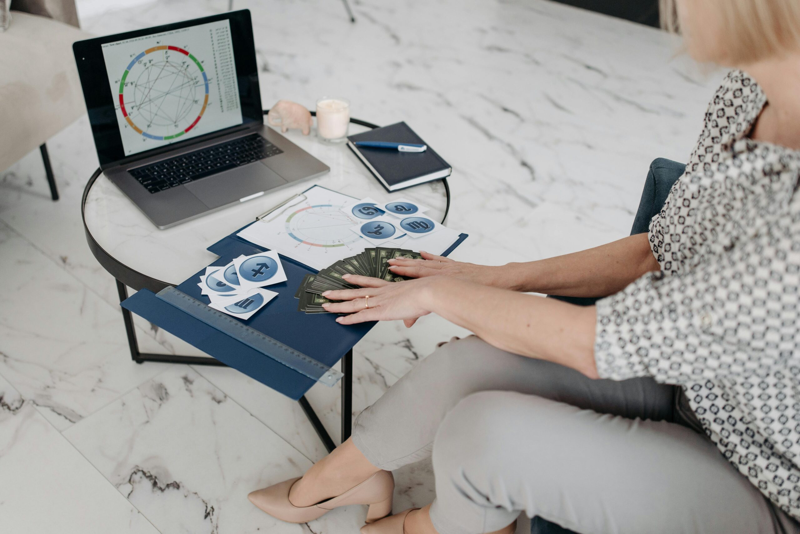 Astrology scene with a woman using a laptop and tarot cards in a modern living room.